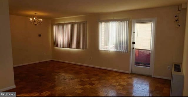 unfurnished room with dark parquet floors and an inviting chandelier