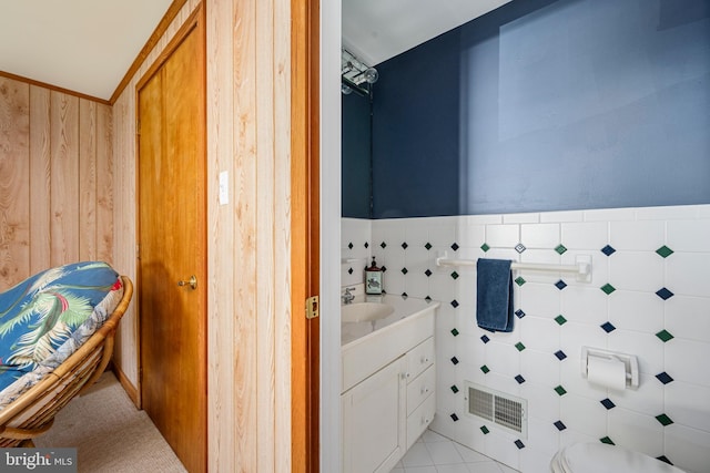 bathroom with tile patterned floors, wood walls, vanity, and tile walls