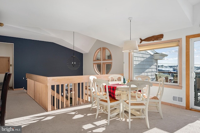 carpeted dining room featuring vaulted ceiling