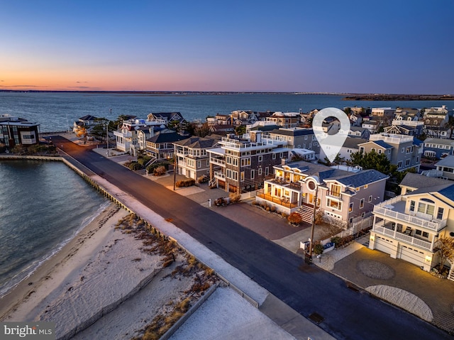 aerial view at dusk featuring a beach view and a water view