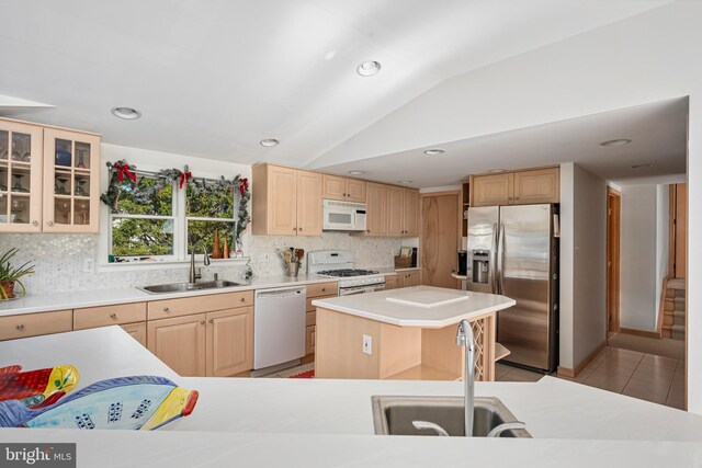 kitchen featuring lofted ceiling, a center island, white appliances, and sink