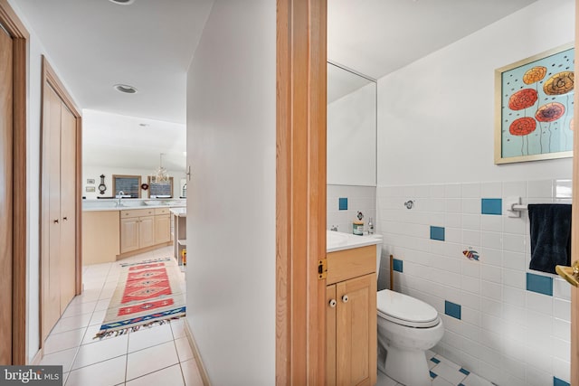 bathroom with tile patterned flooring, vanity, toilet, and tile walls