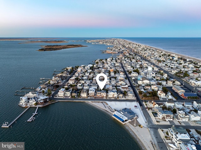 aerial view at dusk with a view of the beach and a water view