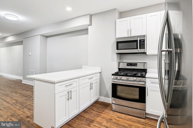 kitchen featuring white cabinets, appliances with stainless steel finishes, kitchen peninsula, and dark wood-type flooring