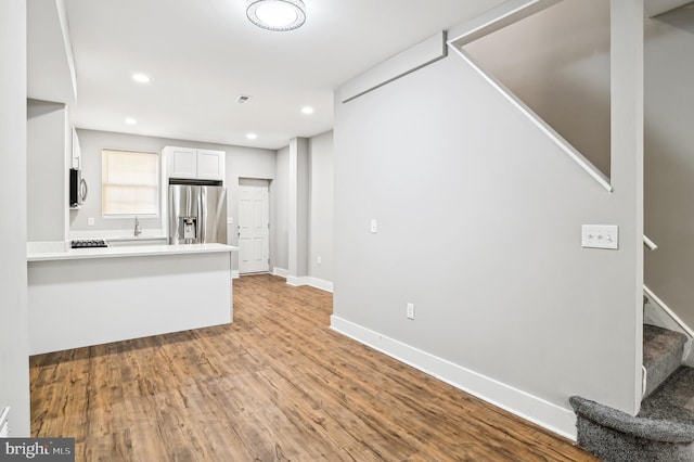 kitchen featuring white cabinets, kitchen peninsula, stainless steel refrigerator with ice dispenser, and light hardwood / wood-style flooring