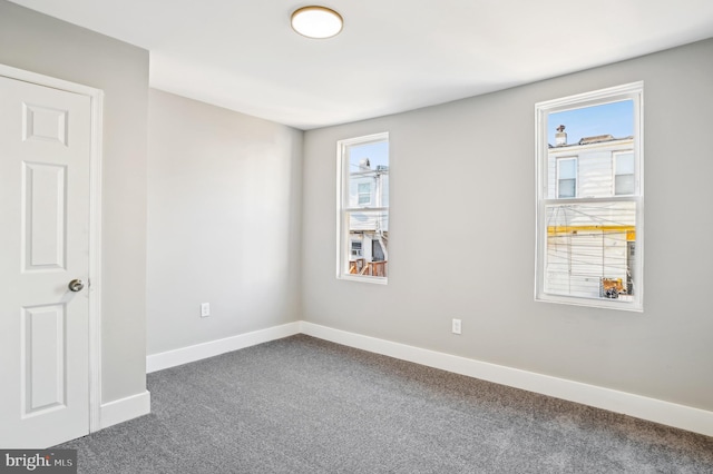 unfurnished room featuring a wealth of natural light and dark colored carpet