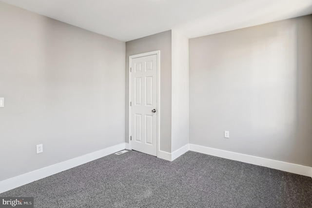 unfurnished room featuring dark colored carpet