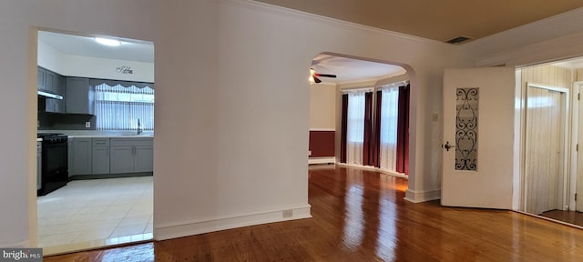 corridor with crown molding, baseboard heating, sink, and light hardwood / wood-style flooring