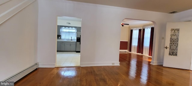 hallway with wood-type flooring, baseboard heating, and ornamental molding