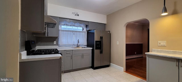 kitchen with black range oven, sink, hanging light fixtures, stainless steel fridge, and a baseboard radiator