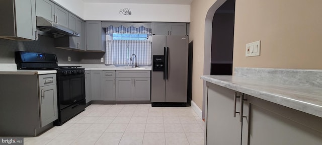 kitchen with gray cabinetry, sink, black gas range oven, and stainless steel refrigerator with ice dispenser