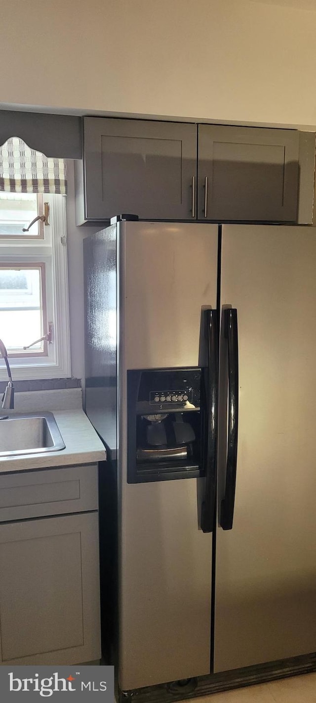 kitchen with gray cabinetry, stainless steel fridge, and sink