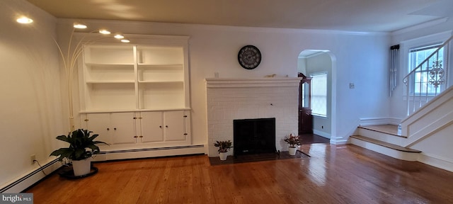 unfurnished living room featuring hardwood / wood-style floors, crown molding, a fireplace, and a baseboard radiator