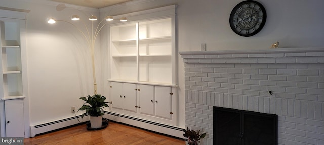 interior details with a fireplace, wood-type flooring, built in shelves, and a baseboard heating unit