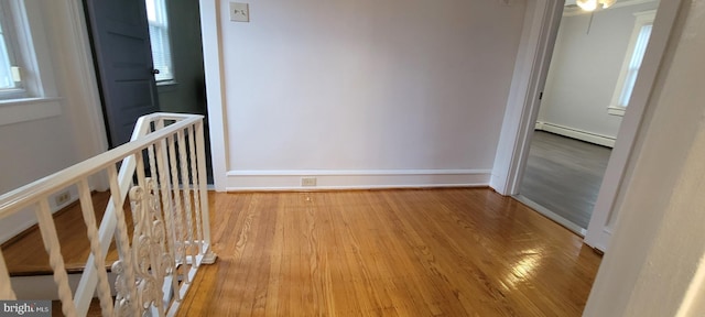 hallway with light wood-type flooring and baseboard heating