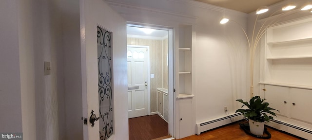 corridor featuring ornamental molding, wood-type flooring, and a baseboard heating unit