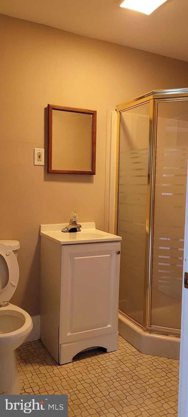 bathroom featuring tile patterned floors, vanity, toilet, and a shower with shower door