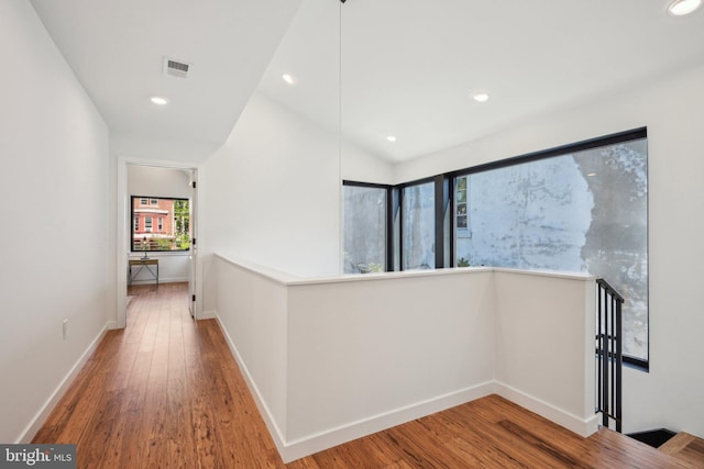 hallway featuring wood finished floors, recessed lighting, baseboards, and lofted ceiling