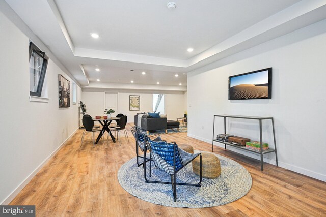 sitting room with light wood-style floors, recessed lighting, a tray ceiling, and baseboards
