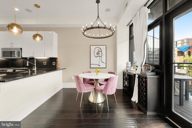 dining room with dark wood-style flooring, an inviting chandelier, and baseboards