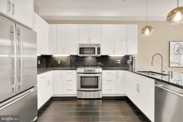 kitchen with white cabinetry, stainless steel appliances, a sink, and pendant lighting