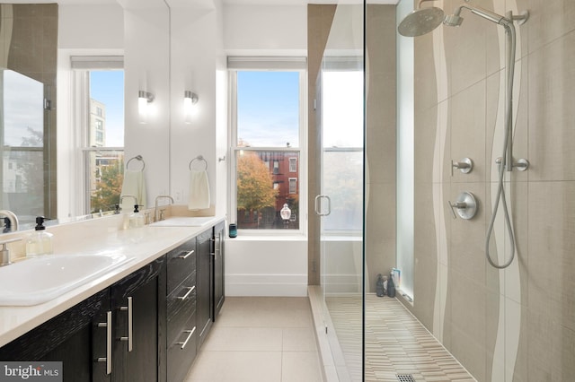 bathroom with double vanity, tile patterned flooring, a tile shower, and a sink