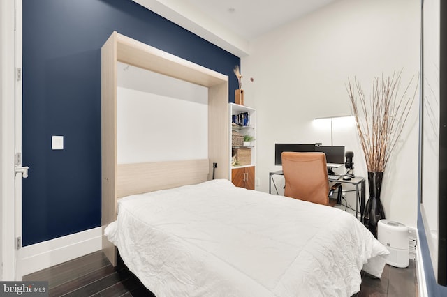 bedroom featuring baseboards and dark wood-type flooring