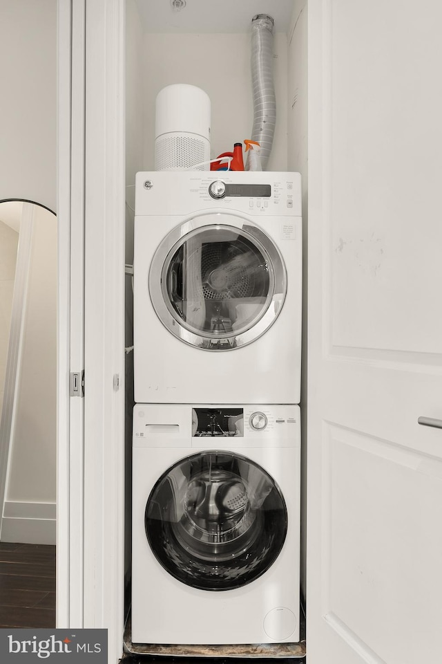 washroom featuring wood finished floors, stacked washer and clothes dryer, and laundry area