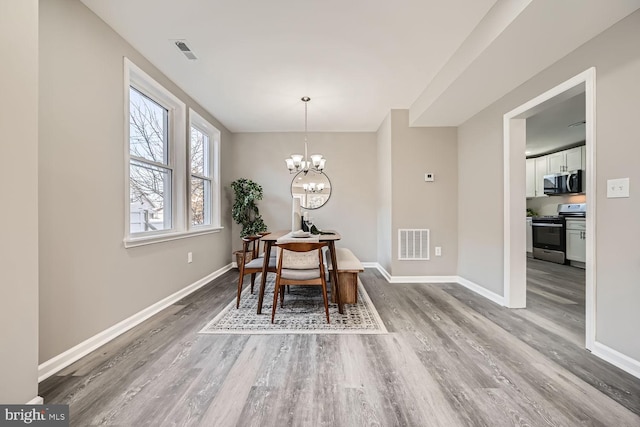 dining room with wood-type flooring and an inviting chandelier