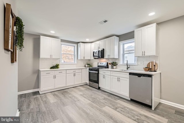 kitchen with a wealth of natural light, white cabinetry, and appliances with stainless steel finishes