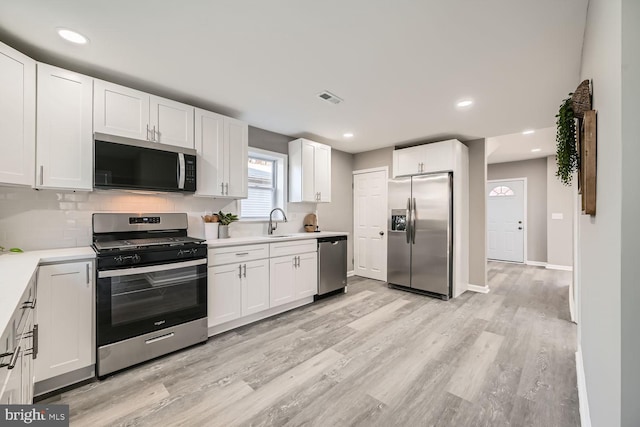 kitchen with light countertops, visible vents, appliances with stainless steel finishes, light wood-style floors, and a sink