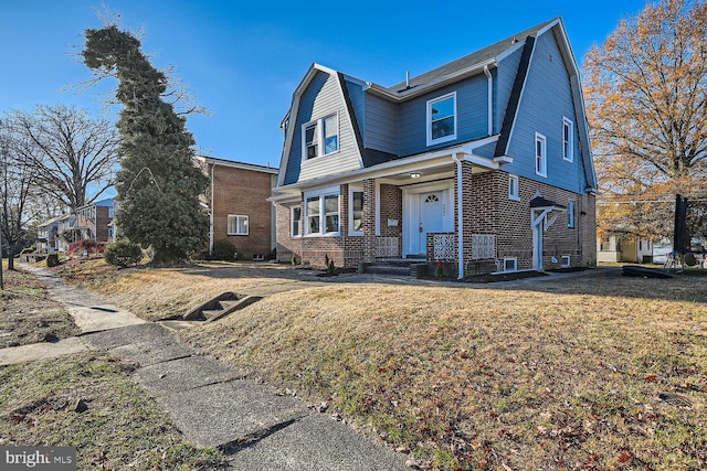 dutch colonial with a front lawn, brick siding, and a gambrel roof