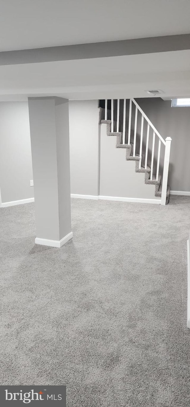 finished basement featuring carpet floors, baseboards, and stairway