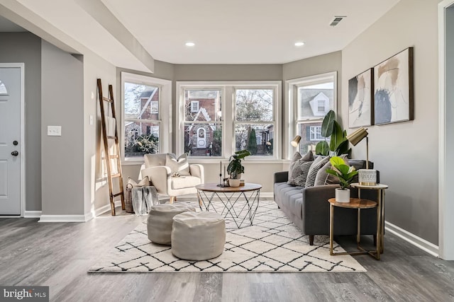 living area with recessed lighting, wood finished floors, visible vents, and baseboards