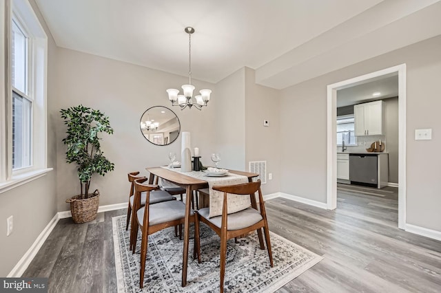 dining space featuring a chandelier, light wood-style flooring, visible vents, and baseboards