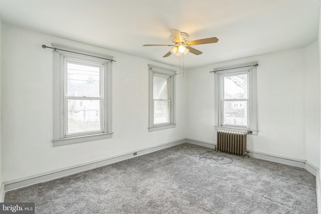 empty room featuring carpet floors, plenty of natural light, radiator, and ceiling fan