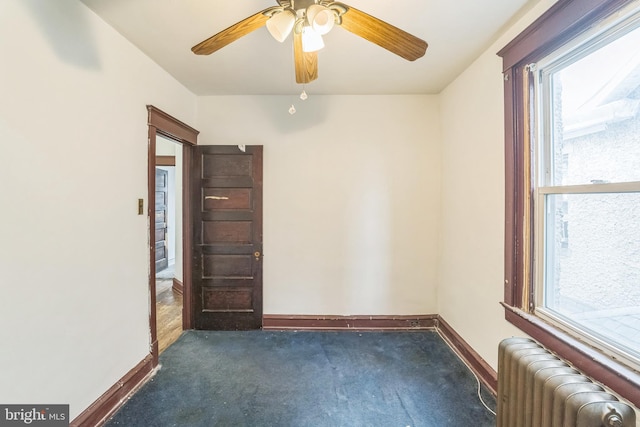 carpeted spare room with ceiling fan and radiator