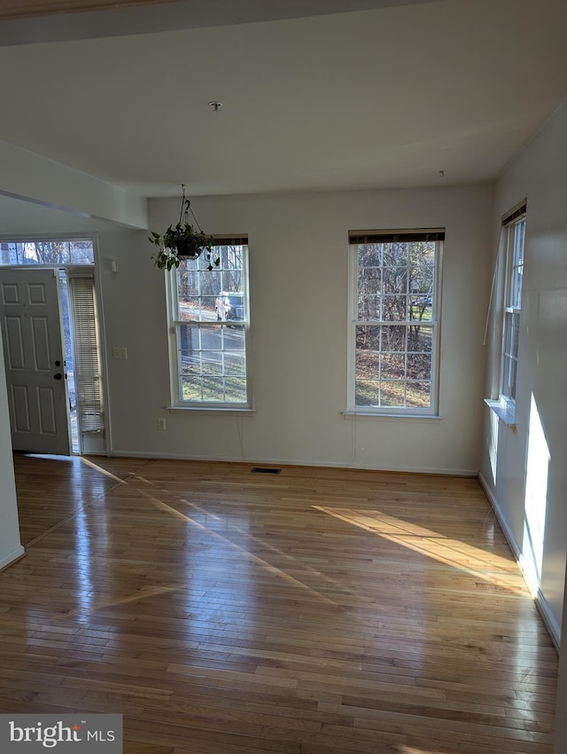 unfurnished dining area featuring wood-type flooring and an inviting chandelier