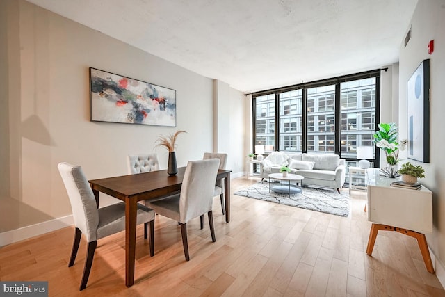 dining space featuring expansive windows and light hardwood / wood-style floors