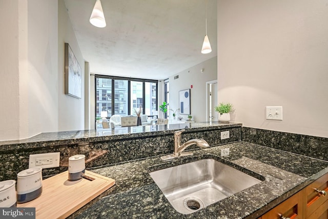 kitchen with decorative light fixtures, dark stone countertops, and sink