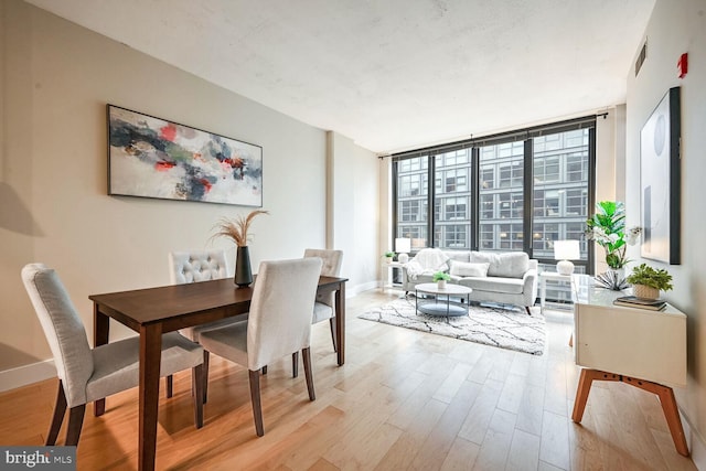 dining space featuring light hardwood / wood-style floors and a wall of windows