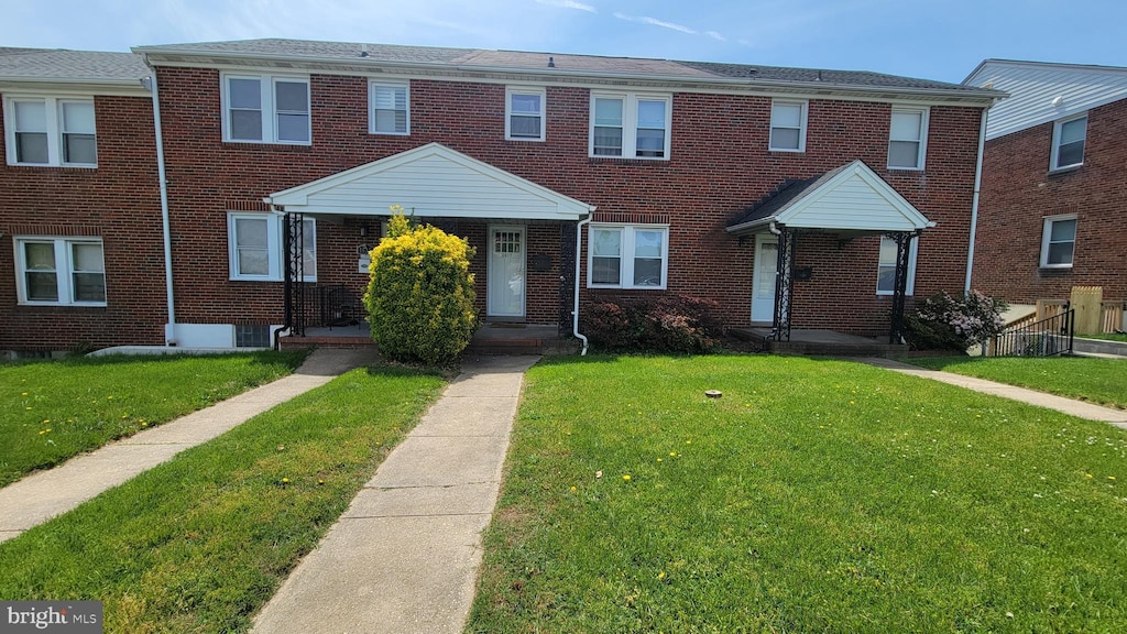 townhome / multi-family property with a front lawn and brick siding