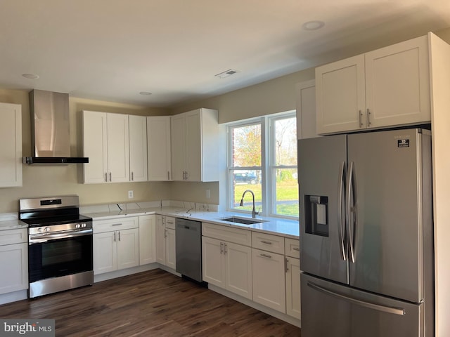 kitchen featuring visible vents, appliances with stainless steel finishes, white cabinets, wall chimney exhaust hood, and a sink