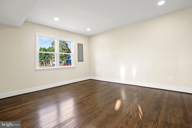 empty room featuring electric panel, dark wood-style floors, recessed lighting, and baseboards