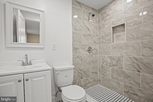 bathroom with tiled shower, toilet, and vanity