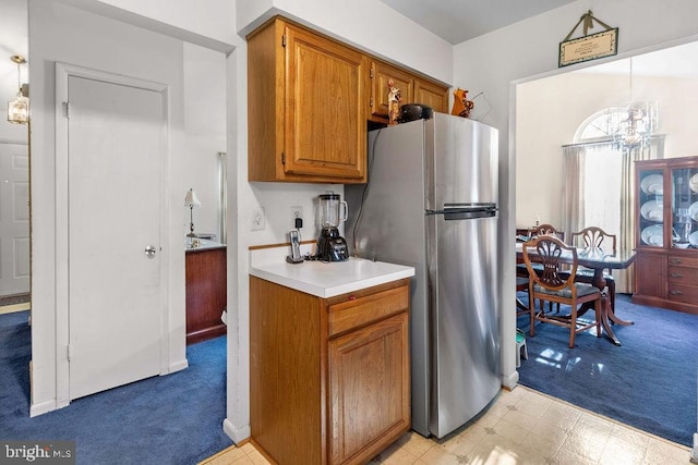 kitchen featuring pendant lighting, light colored carpet, stainless steel refrigerator, and a chandelier