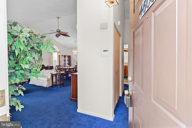 foyer with dark colored carpet, ceiling fan with notable chandelier, and high vaulted ceiling