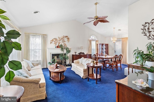 living room with ceiling fan with notable chandelier, dark carpet, a tile fireplace, and vaulted ceiling