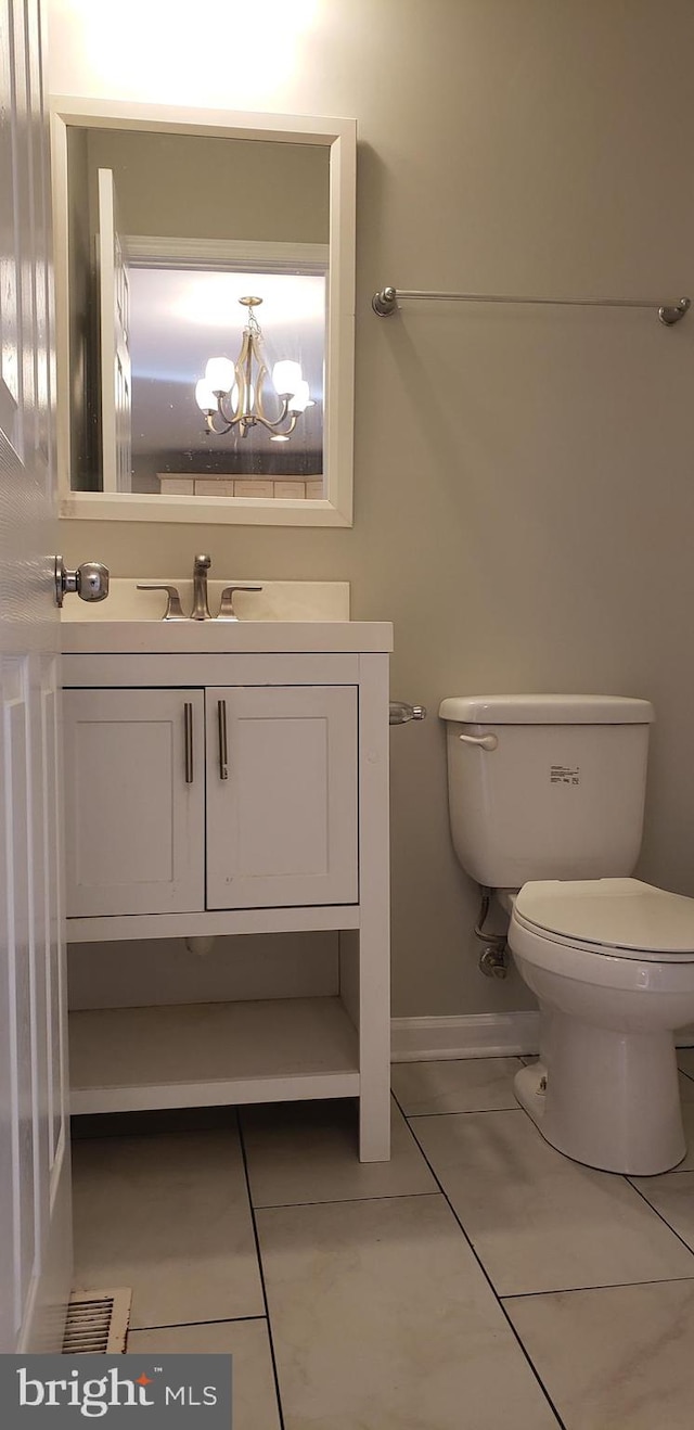 bathroom featuring tile patterned flooring, a notable chandelier, toilet, and vanity