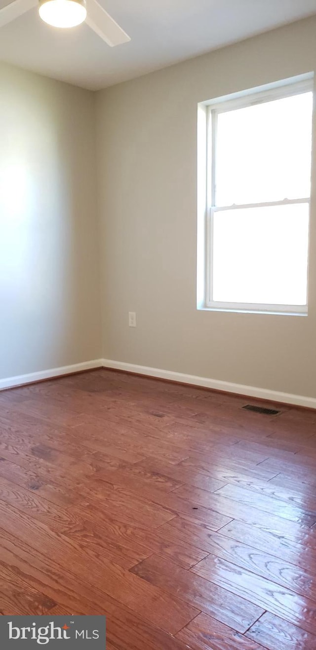 empty room featuring hardwood / wood-style flooring, ceiling fan, and a healthy amount of sunlight